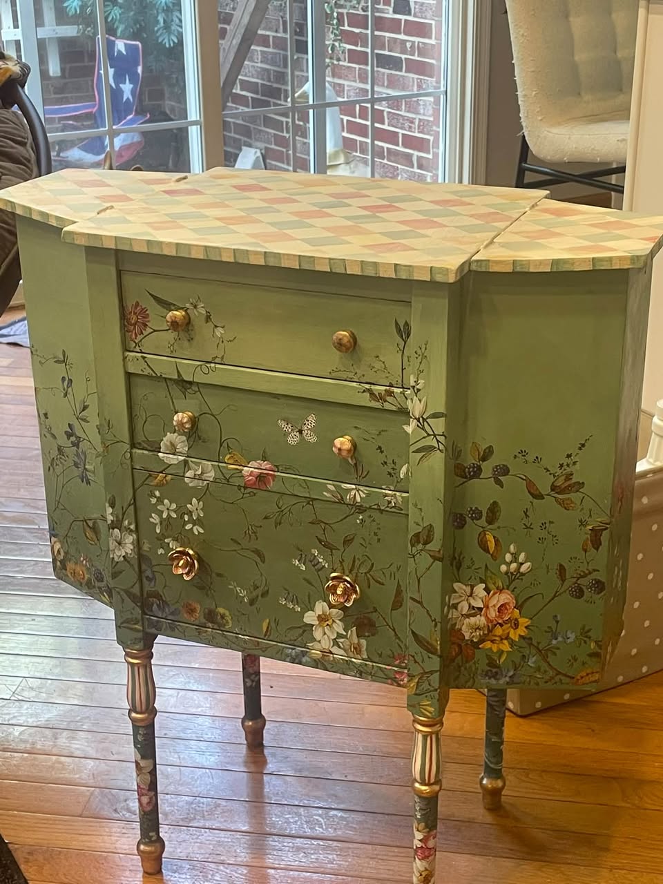 Finished Martha Washington sewing cabinet in soft green with floral artwork, gold hardware, and a hand-painted harlequin top